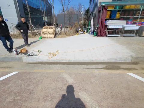 아파트 단지 앞 화강석 포장 구간을 새로 마감하고 밧줄로 통제선을 쳐 둔 완료 직후 모습