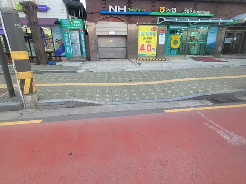 마트 입구 앞 보도에 노란 점자유도블록 라인이 선명하게 이어진 모습